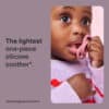 Tommee Tippee Ultra Light Silicone Soother 0-6M in pink, held by a baby wearing a cozy sweater, showcasing its lightweight