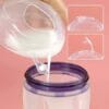 Haakaa 2x Ladybug Breast Milk Collector with a clear design, pouring milk into a storage bag, showcasing its functionality.