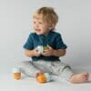 Nutribullet Baby in use with a smiling toddler holding colorful containers, sitting on a light background.
