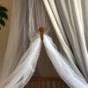 The Stella Clip in Beach Bébé securely holds a sheer netting draped over a crib, showcasing its elegant design.