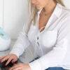 Spectra Handsfree Cup Set in use, featuring a woman working on a laptop with a breast pump nearby.