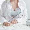 Spectra Handsfree Cup Set in use, featuring a woman wearing a nursing bra while writing at a desk.