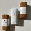 Kid Raine muslin burp cloths in Harper and Sienna colors, neatly rolled with branded labels, showcasing soft texture.