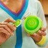 Munchkin bottle and cup cleaning brush set in green, featuring a person using the brush with a circular cleaning tool.