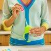 Munchkin bottle and cup cleaning brush set in use, featuring a person holding a green brush with a colorful handle in a