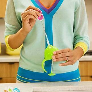 Munchkin bottle and cup cleaning brush set in use, featuring a person holding a green brush with a colorful handle in a