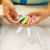 Munchkin bottle and cup cleaning brush set featuring four colorful brushes held above a soapy sink.