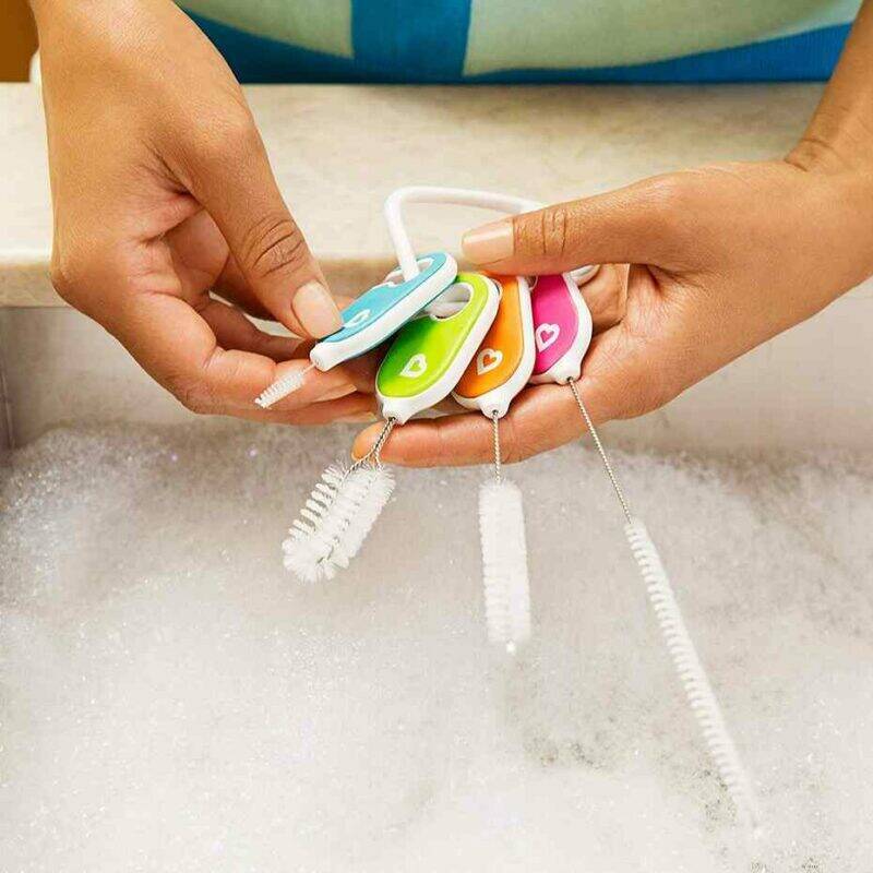 Munchkin bottle and cup cleaning brush set featuring four colorful brushes held above a soapy sink.