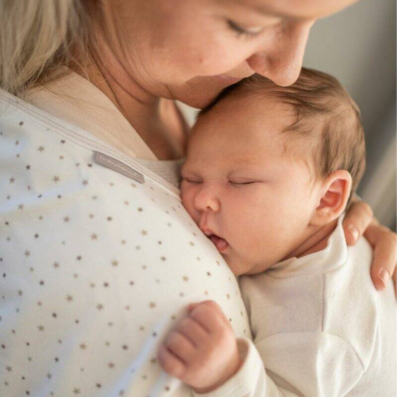 Baby Sense Burp Cloth Set in blue, pink, and stone, shown in a cozy lifestyle setting with a parent holding a sleeping baby.