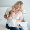 Baby Sense Burp Cloth Set in white with grey stars, shown being used by a mother holding her baby on a bed.