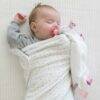 Baby Sense Taglet in blue and pink, featuring soft fabric and tags, with a sleeping baby wrapped in a cozy blanket.
