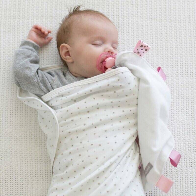 Baby Sense Taglet in blue and pink, featuring soft fabric and tags, with a sleeping baby wrapped in a cozy blanket.