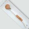Kid Raine silicone dummy clip in blues, neutrals, and pinks with wooden beads spelling "KIND." Ideal for pacifiers.