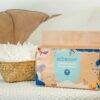 Eco Boom Joy Bamboo Baby Nappies for newborns, packaged in a colorful box, placed next to a basket of diapers.