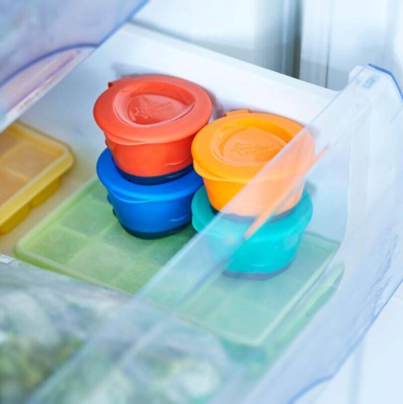 Tommee Tippee Pop Up Freezer Pots in vibrant colors stacked in a freezer tray, showcasing organized baby food storage.