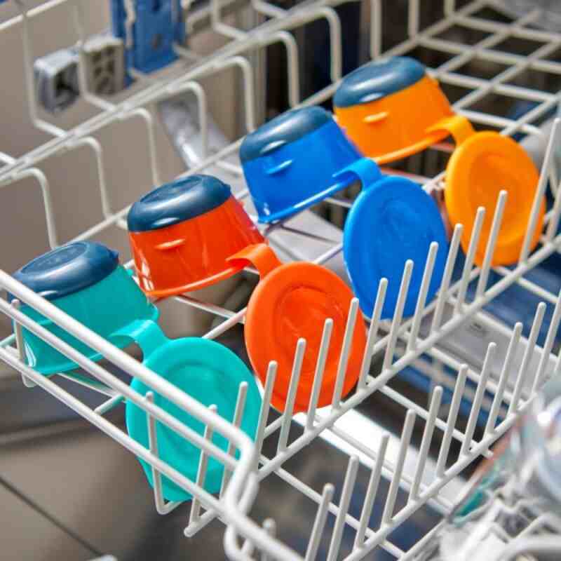 Tommee Tippee Pop Up Freezer Pots in orange and blue, neatly arranged in a dishwasher's top rack.