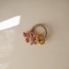 FRIGG + Mushie Nature Teething Ring in soft pink, beige, and yellow with playful shapes for soothing teething relief.