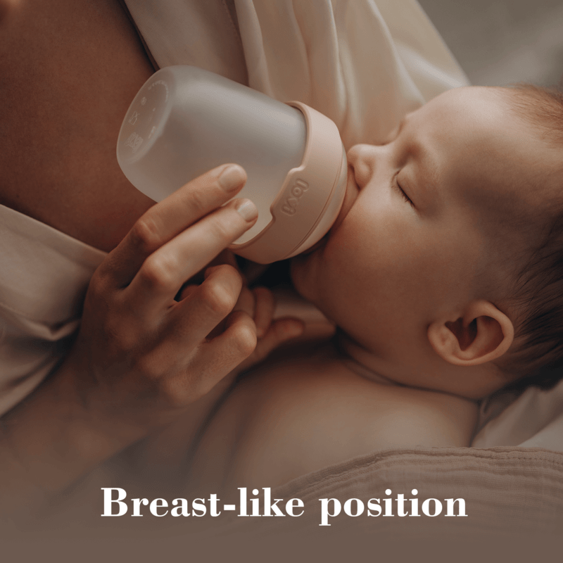 Difrax LOVI Mammafeel Bottle 150ml in a soft pink hue, held by a parent while a baby feeds in a cozy setting.