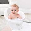 Shnuggle Baby Bath in white, featuring a smiling baby enjoying a bubble bath, set in a cozy living room.