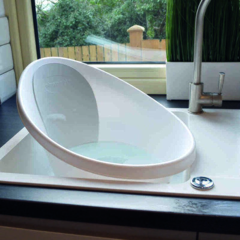 Shnuggle Baby Bath in Blossom Pink, angled view resting in a sink with a modern kitchen backdrop.