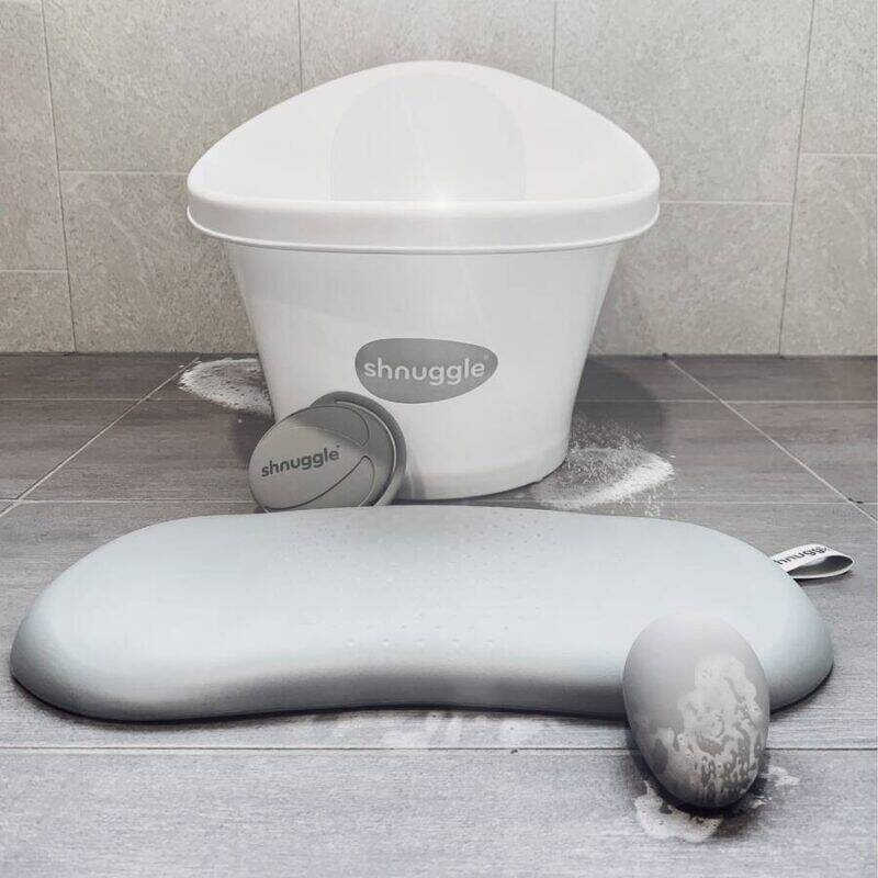 Shnuggle Kneeler in grey with a matching bath bucket and a small accessory, set on a tiled floor with a clean aesthetic.
