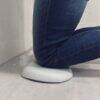 Shnuggle Kneeler in a bathroom setting, supporting a person kneeling on a soft, cushioned surface against a tiled wall.