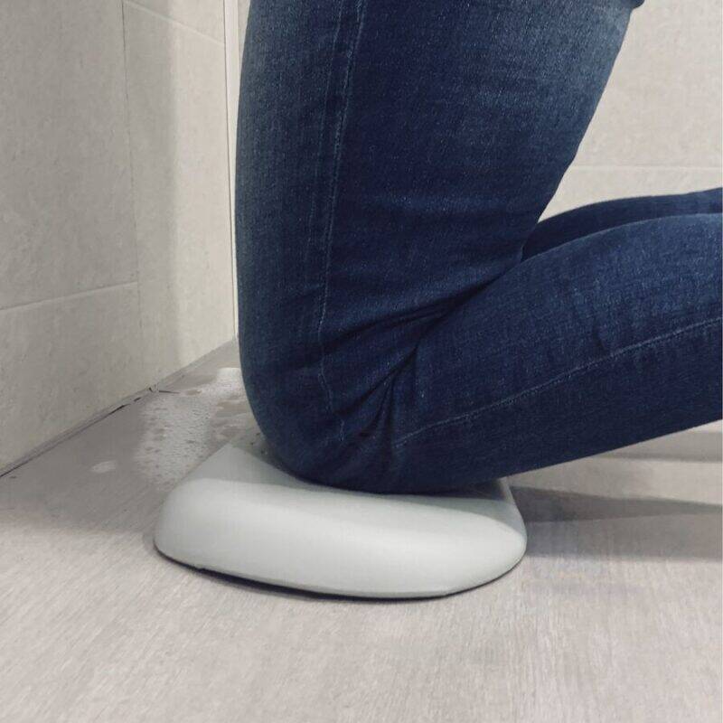 Shnuggle Kneeler in a bathroom setting, supporting a person kneeling on a soft, cushioned surface against a tiled wall.