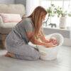Shnuggle Baby Bath in white, with a parent bathing a baby in a cozy living room setting.