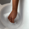 Shnuggle Baby Bath in Blossom Pink, showing a hand adjusting the drainage plug inside the tub.