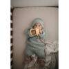 Mushie No-Drop Sun Teether in Sunshine, held by a baby in a cozy outfit, lying on a soft blanket in a crib.