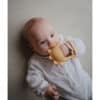 Mushie No-Drop Sun Teether in Sunshine color, held by a baby, featuring a sun shape and textured grip.