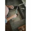 Mushie Silicone Baby Bottle Brush in Cambridge Blue being used in a sink, with hands holding a bottle and brush.
