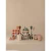 Mushie Silicone Baby Bottle Brush in blush among various baby utensils and dishes in soft pastel colors on a neutral