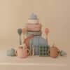 Mushie Silicone Baby Bottle Brush in blush, surrounded by various baby items in a soft, neutral setting.