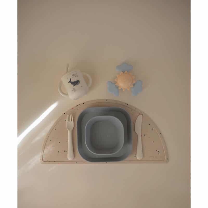 Mushie Dinnerware Cutlery Set in blush and cloud colors, featuring a plate, bowl, fork, and knife on a playful mat.