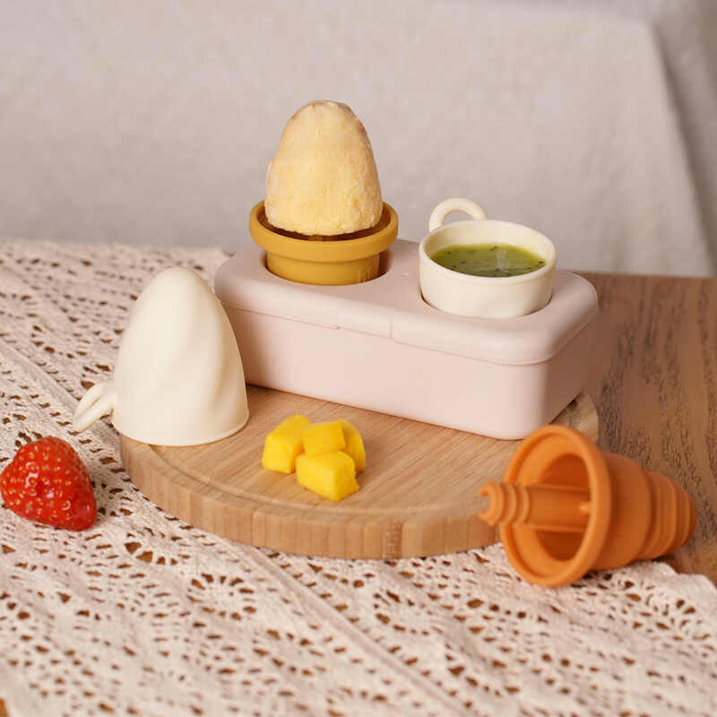 Haakaa Freeze-'n-Sip Ice Cream Mould Set in marigold and slate, featuring ice cream molds and a storage container on a