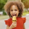 Haakaa Freeze-'n-Sip Ice Cream Mould Set in marigold, used by a smiling child enjoying a homemade ice cream treat outdoors.