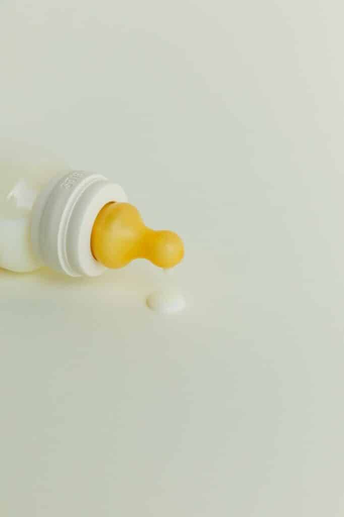 BIBS Baby Bottle Light in soft yellow with a silicone nipple and a small drip of milk on a light background.