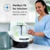Baby Brezza Bottle Washer Pro in a kitchen setting, with a woman using it to clean baby bottles. Compact and sleek design.
