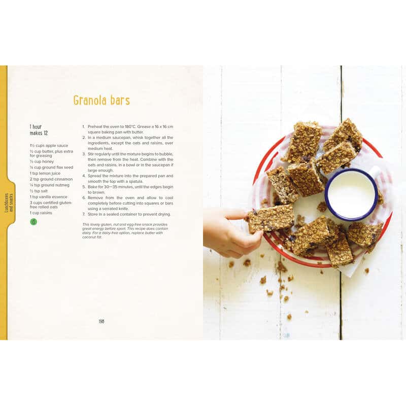 Open cookbook page featuring granola bar recipe with a hand reaching for a bar and a glass of milk on a red plate.