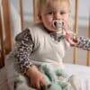 Maccie Winter Sleep Sack TOG 2 in Oatmeal Beige, worn by a baby in a crib, holding a soft toy and pacifier.