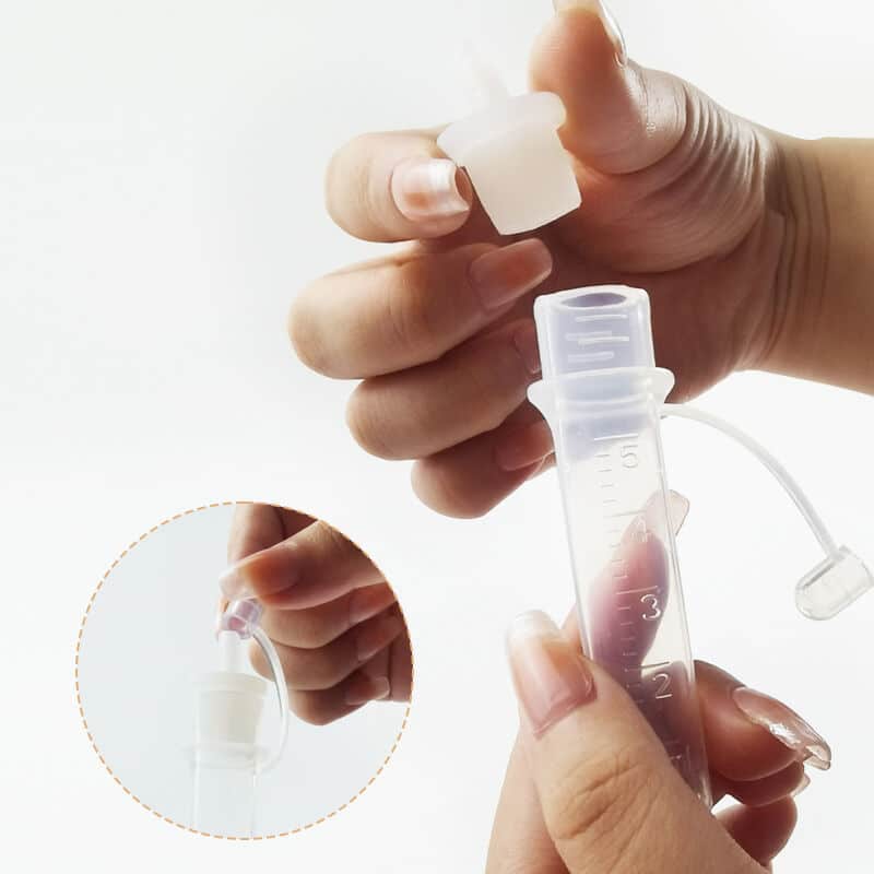 All Things Breastfeeding Colostrum Collector with a clear tube and cap, held in hands, showcasing its practical design.