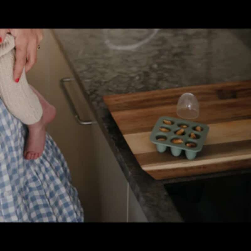 Mushie Fresh Food Feeder Freezer Tray in Cambridge Blue, shown on a wooden countertop with a person holding a baby.