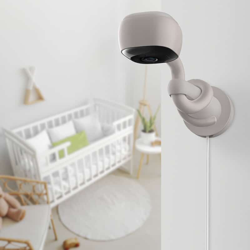 Hubble AI Vision security camera in soft beige, mounted on a wall near a nursery with a crib and soft decor.
