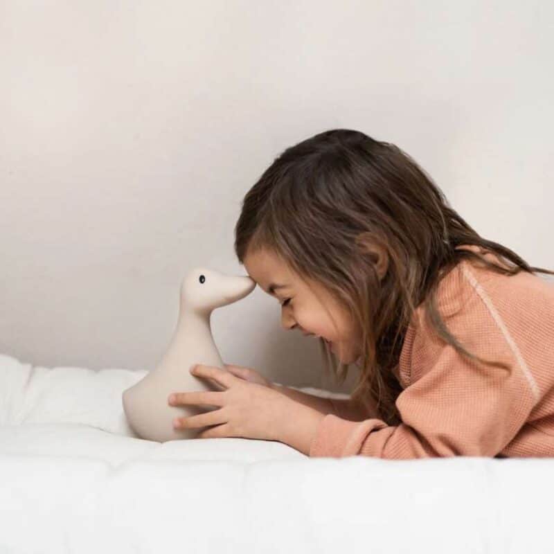 Flow Amsterdam Night Light featuring Liva character, a soft beige duck, with a child joyfully interacting in a cozy setting.