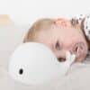 Flow Amsterdam Night Light featuring Liva the whale, soft white design, with a child resting beside it in a cozy bedroom