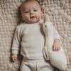 Flow Amsterdam Liva Heartbeat Rechargeable Comforter in beige, featuring a cozy texture, with a baby snuggling beside it.