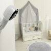 Hubble Nursery Pal Cloud monitor mounted on wall, overlooking a cozy nursery with a crib and plush toys.