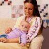 BIBS Studio Colour Pacifier 2 Pack in Baby Blue Dusty Blue and Jasmine Fossil Grey, held by a smiling mother with her baby.