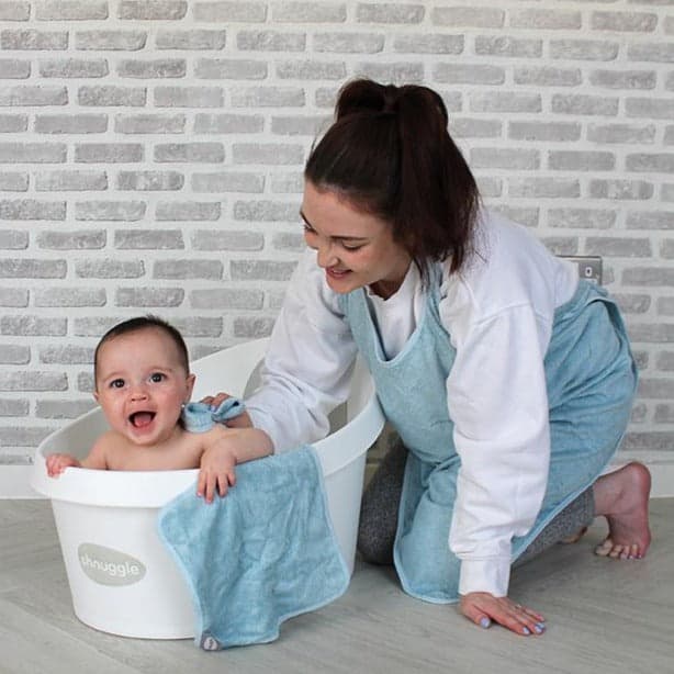 Shnuggle Bamboo Wearable Baby Towel in blue, featuring a smiling baby in a bath with a parent nearby.